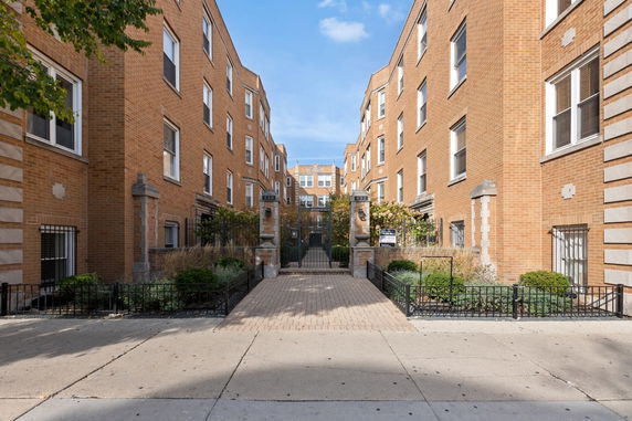 Front view of a multi-story brick apartment building with gated entrance.