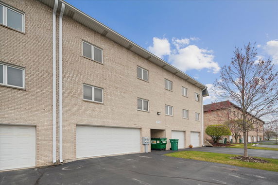Front view of a multi-story brick building with multiple garage doors and windows.