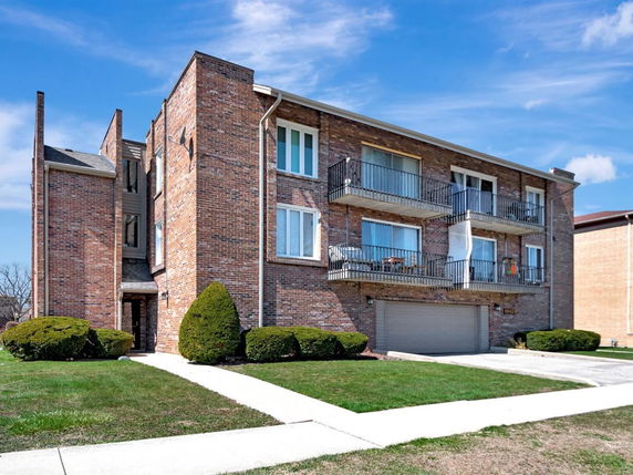Front view of a multi-story brick building with balconies.