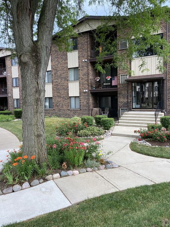 Front view of a multi-story brick residential building with balconies.
