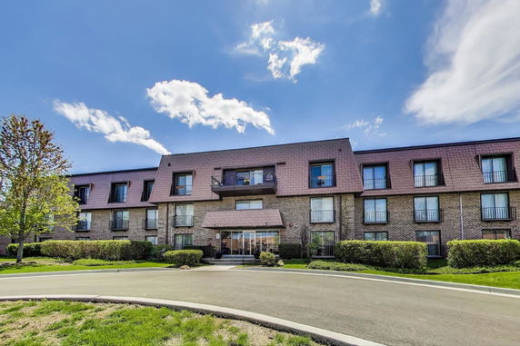 Front view of a multi-story brick building with balconies and large windows.