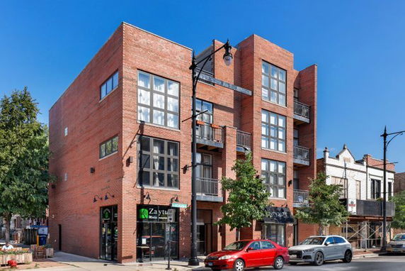 Front view of a multi-story brick building with large windows and balconies.