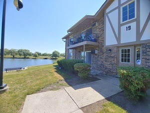 Front view of a two-story building with brick and wood paneling, beside a lake.