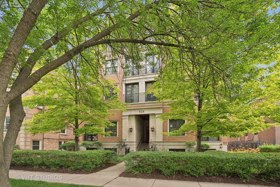 Front view of a multi-story brick building with trees in front.