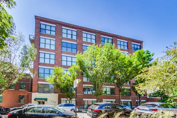 Front view of a multi-story brick building with large windows.