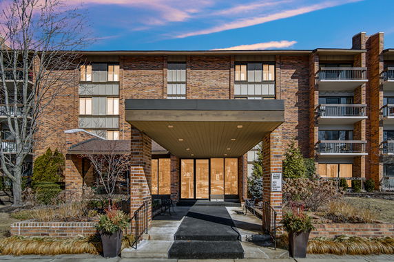 Front view of a multi-story brick residential building with balconies.