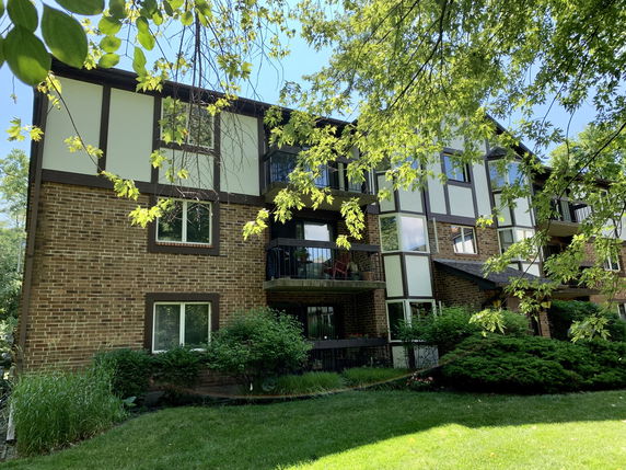 Front view of a three-story residential building with brick and panel facade, featuring balconies.
