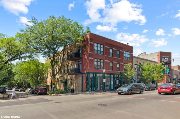 Front view of a three-story brick building on a street corner.