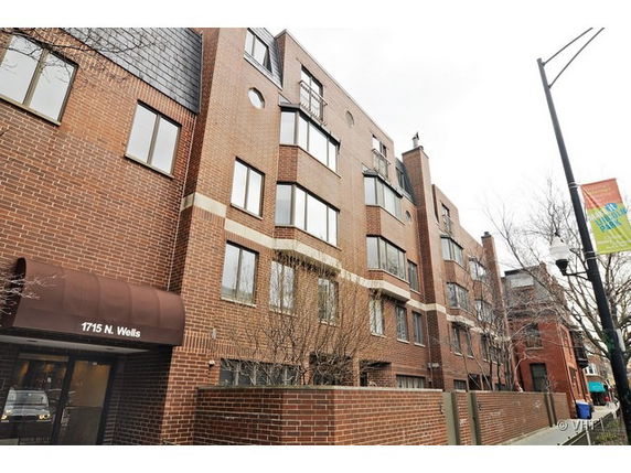 Front view of a multi-story brick building with multiple windows and a canopy entrance.