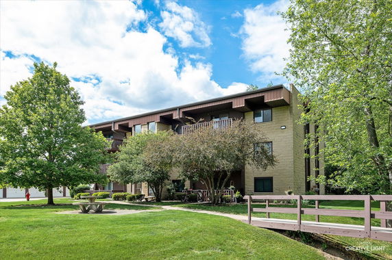 Front view of a multi-story building with balconies surrounded by trees.