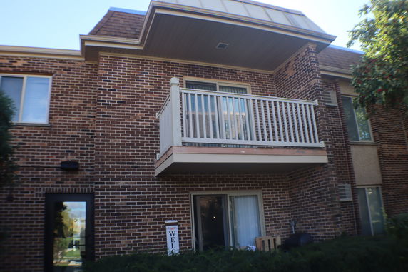 Front view of a multi-story brick building with a balcony.
