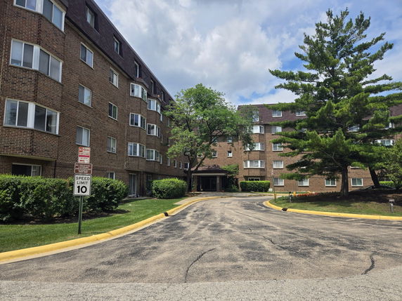 Front view of a multi-story brick apartment building with bay windows.