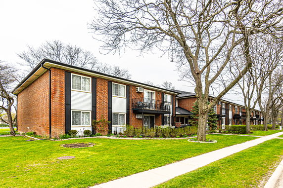 Front view of a two-story brick apartment building with balconies.
