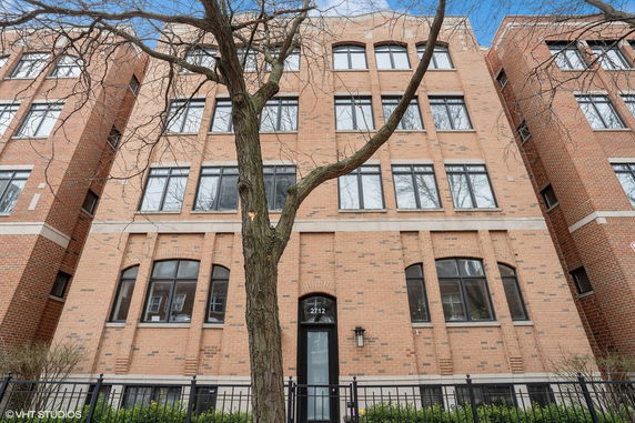 Front view of a multi-story brick building with large windows.