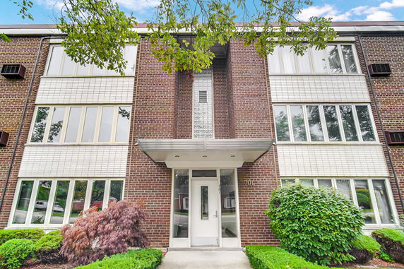 Front view of a multi-story brick building with large windows and a central entrance.