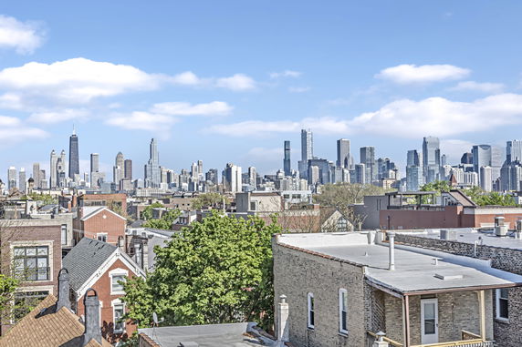 Panoramic view of city skyline with rooftops in the foreground.