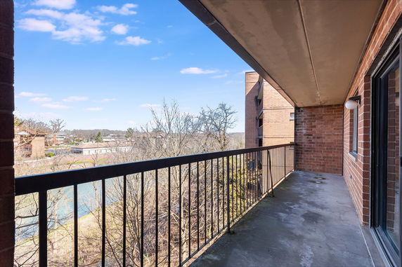 Balcony view from a building overlooking surrounding trees and buildings.