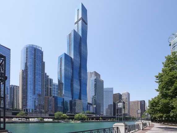 Front view of a modern skyscraper amid other tall buildings.