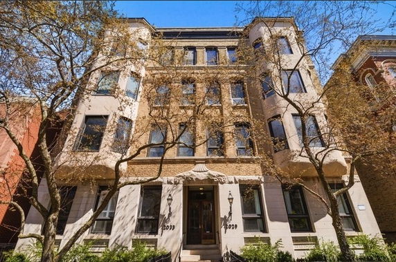 Front view of a multi-story residential building with bay windows and trees in front.