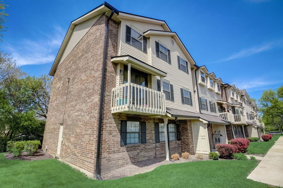 Front view of a multi-story townhouse with a brick exterior and small balconies.