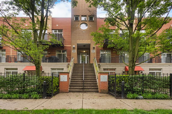 Front view of a multi-story brick building with stairs leading to the entrance.