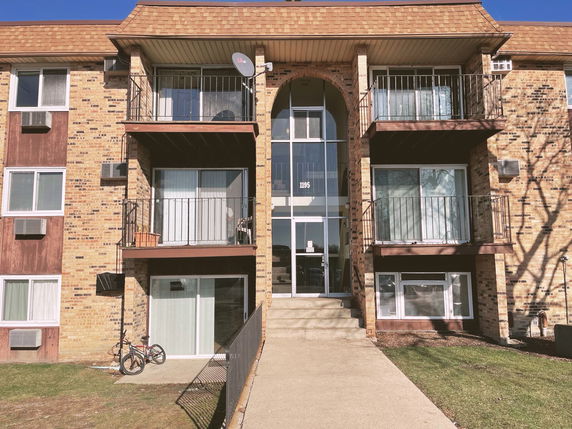 Front view of a multi-story residential building with brick exterior and balconies.