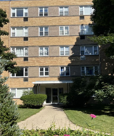 Front view of a multi-story brick building with multiple windows and a central entrance.