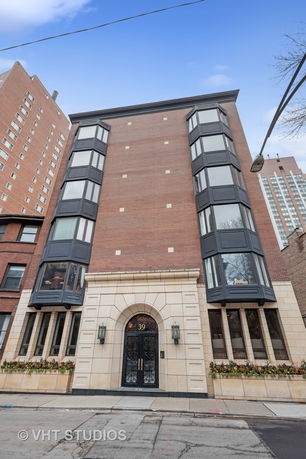 Front view of a multi-story brick building with large windows and an arched entrance.