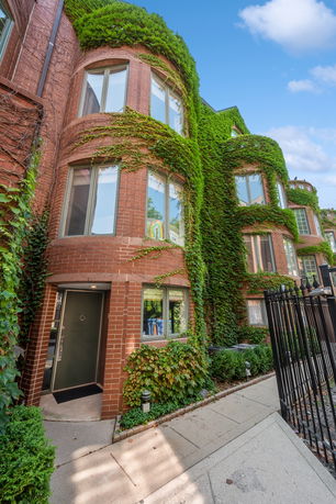 Front view of a multi-story brick house with ivy-covered walls.