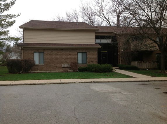 Front view of a two-story building with a brick facade and windows.