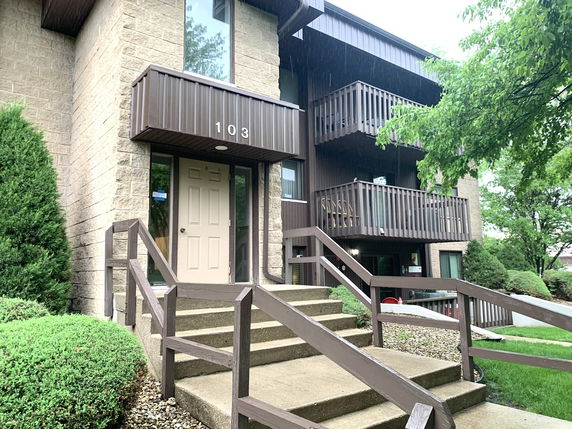 Front view of a multi-story residential building with balconies and a staircase entrance.