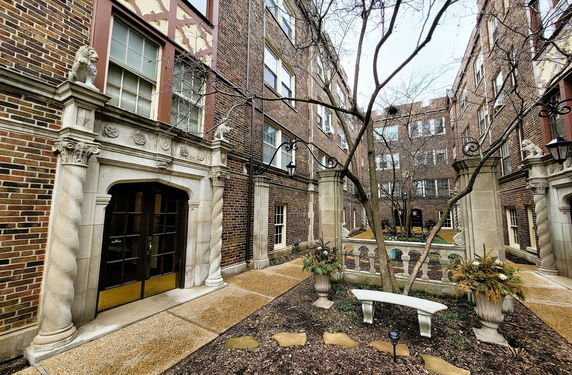 Front view of a multi-story brick building with ornate entrance and decorative elements.