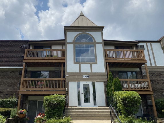 Front view of a multi-story building with wooden balconies and a large central window.