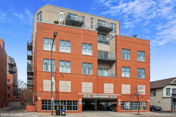 Front view of a multi-story brick building with balconies and public parking entrance.