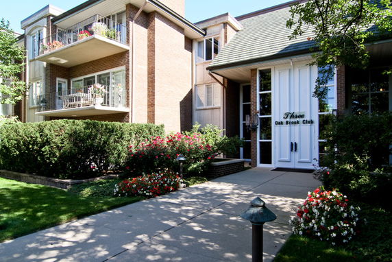 Front view of a multi-story residential building with balconies and landscaped entrance.