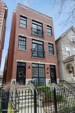 Front view of a multi-story brick building with black window and door accents.