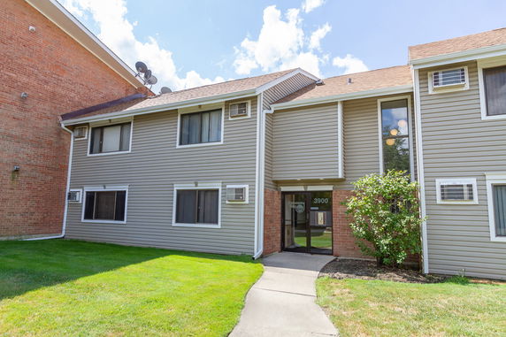 Front view of a two-story apartment building with a central entrance and air conditioning units.