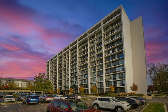 Front view of a multi-story apartment building with a parking area in front.