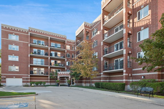 Front view of a multi-story brick apartment building with balconies.