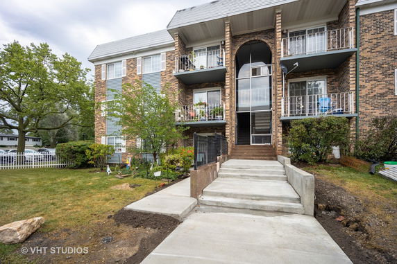 Front view of a multi-story residential building with balconies and a central entrance.