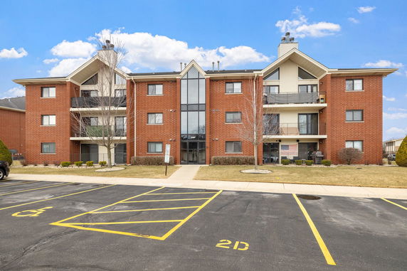 Front view of a three-story apartment building with brick facade and balconies.