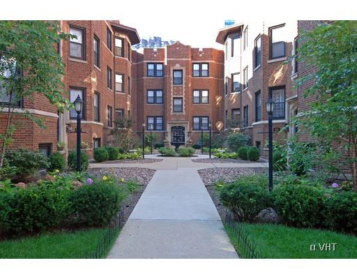 Front view of a red brick multi-story apartment building with landscaped pathways.