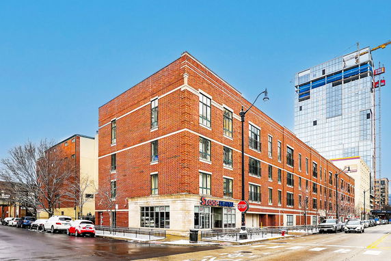 Front view of a multi-story brick commercial building on a city street corner.