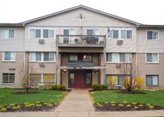 Front view of a three-story apartment building with balconies and multiple windows.