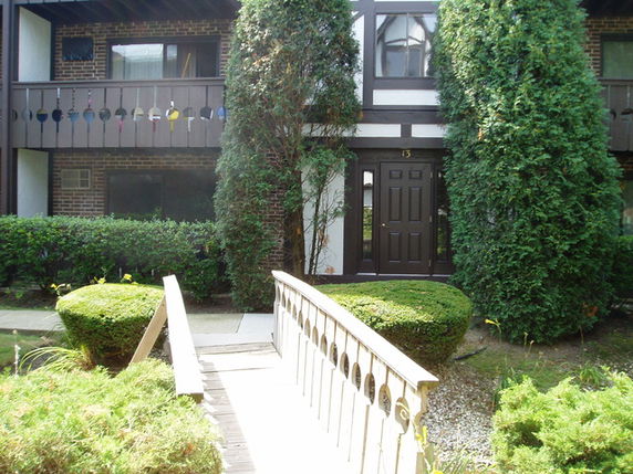Front view of a two-story house with a brown exterior and a bridge leading to the entrance.