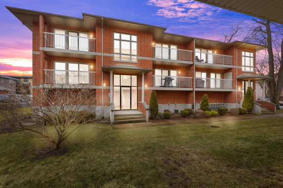 Front view of a multi-story brick apartment building with balconies.