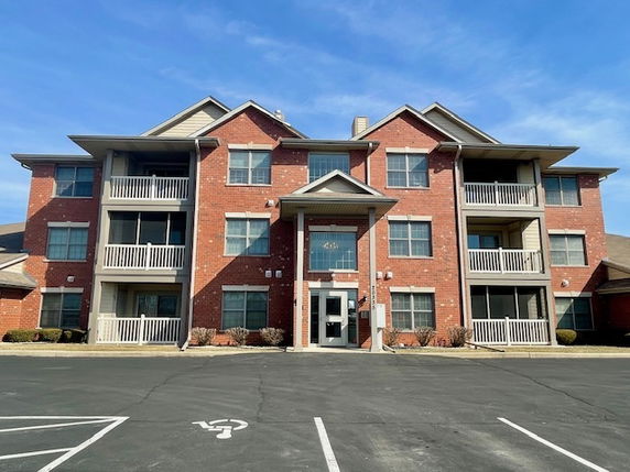 Front view of a three-story brick apartment building with balconies.