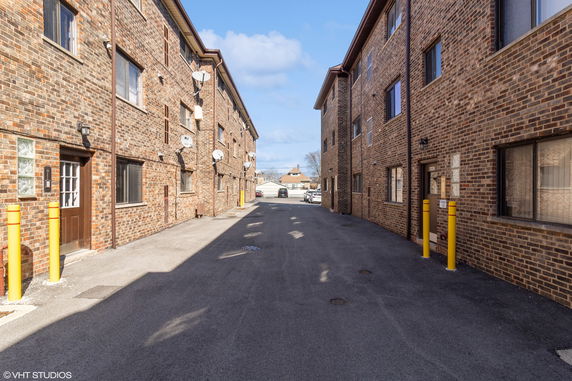 View of two brick apartment buildings with multiple windows facing an alley.