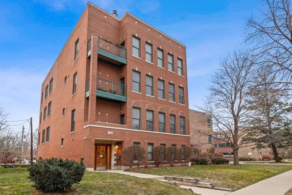 Front view of a three-story brick building with balconies.