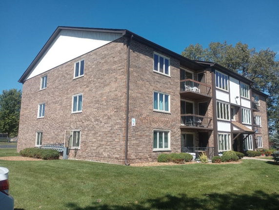 Front view of a multi-story brick apartment building with balconies.